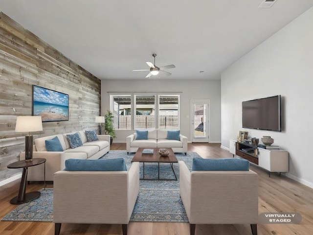 living room featuring wood walls, hardwood / wood-style floors, and ceiling fan