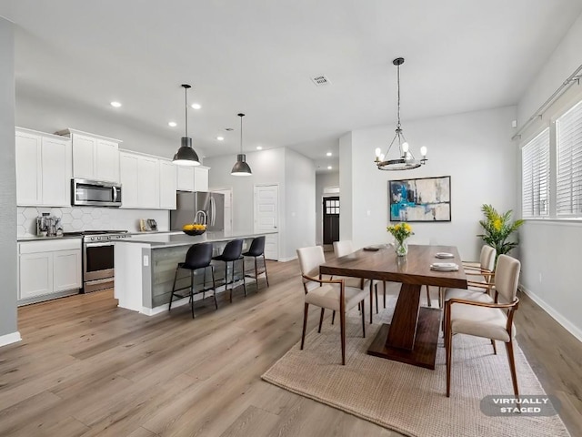 dining space with light hardwood / wood-style flooring and a notable chandelier