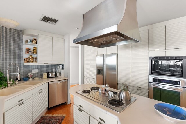 kitchen featuring sink, wall chimney range hood, appliances with stainless steel finishes, white cabinets, and light wood-type flooring