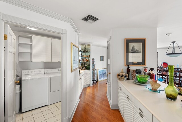 interior space with separate washer and dryer, light tile patterned floors, cabinets, and ornamental molding