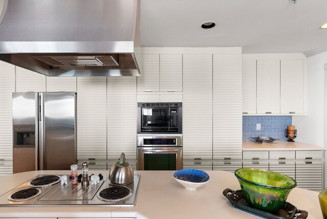 kitchen featuring white cabinets, wall chimney exhaust hood, decorative backsplash, and appliances with stainless steel finishes