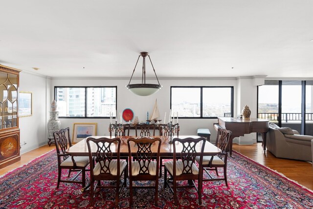 dining space with a wealth of natural light, crown molding, and wood-type flooring