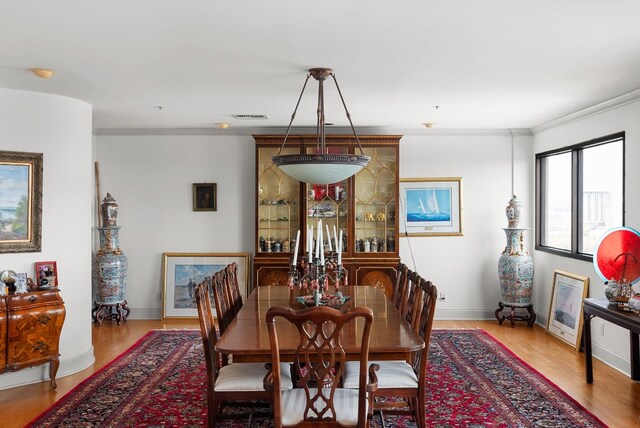 dining room with crown molding and light wood-type flooring