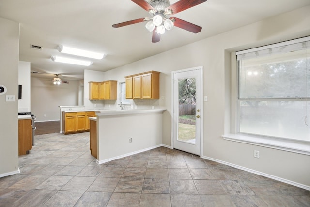 kitchen featuring ceiling fan, kitchen peninsula, sink, and light tile patterned floors