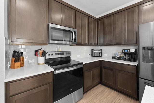 232 Syrah Ct, Leander, TX 78641 - kitchen featuring stainless steel appliances, light countertops, backsplash, and dark brown cabinetry