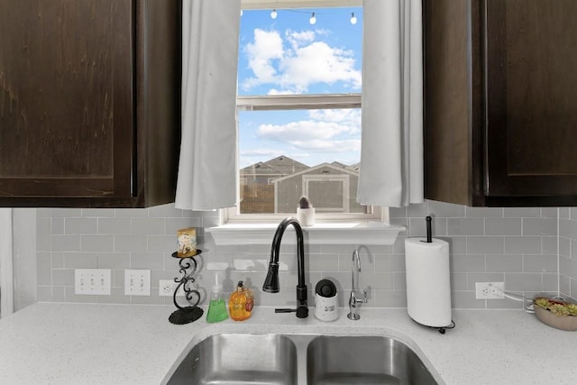 232 Syrah Ct, Leander, TX 78641 - kitchen view of a sink, dark brown cabinets, backsplash, and light stone countertops