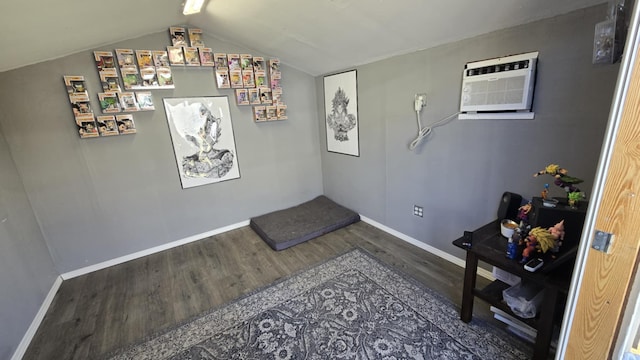 interior space with hardwood / wood-style floors, an AC wall unit, and vaulted ceiling