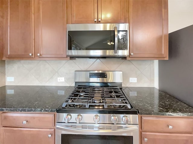 kitchen with backsplash, dark stone countertops, and stainless steel appliances