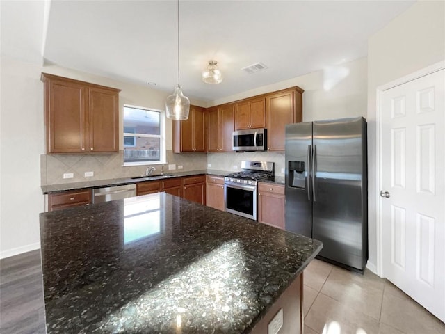 kitchen with pendant lighting, a center island, sink, decorative backsplash, and stainless steel appliances