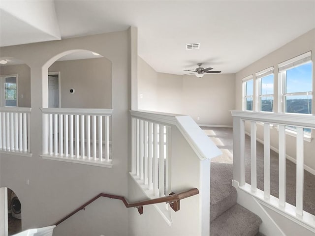 staircase with ceiling fan and carpet floors