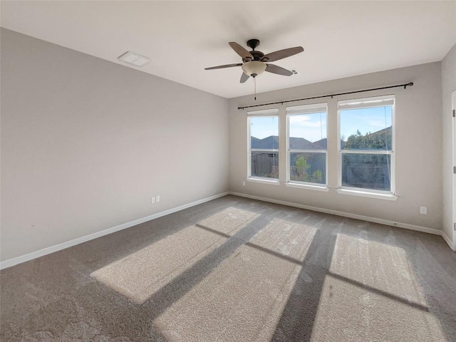 carpeted empty room featuring a mountain view and ceiling fan