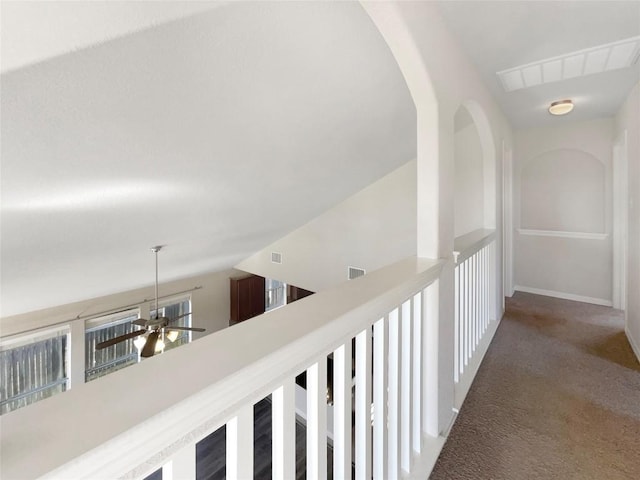 corridor featuring dark colored carpet and lofted ceiling