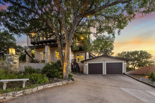 view of front of property featuring concrete driveway, an attached garage, a balcony, and stucco siding