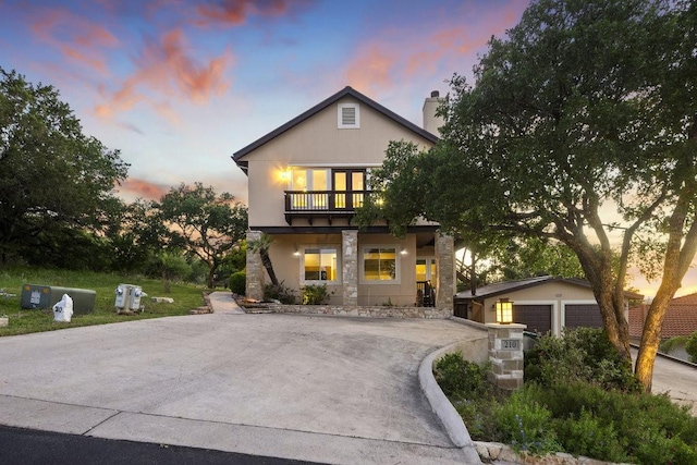 view of front of home featuring an outbuilding, a chimney, a balcony, and stucco siding