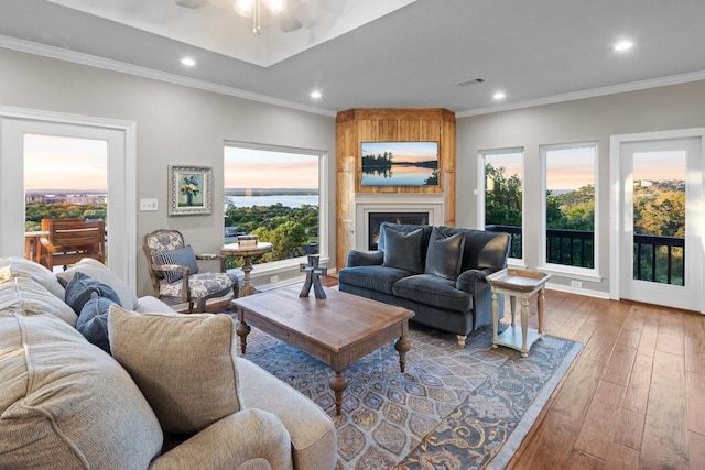 living area with recessed lighting, a large fireplace, wood finished floors, visible vents, and ornamental molding