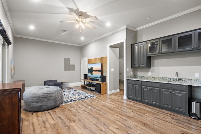 living area with ceiling fan, light wood-style flooring, baseboards, electric panel, and crown molding