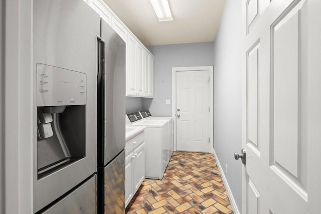 laundry room with brick floor, cabinet space, baseboards, and washer and clothes dryer