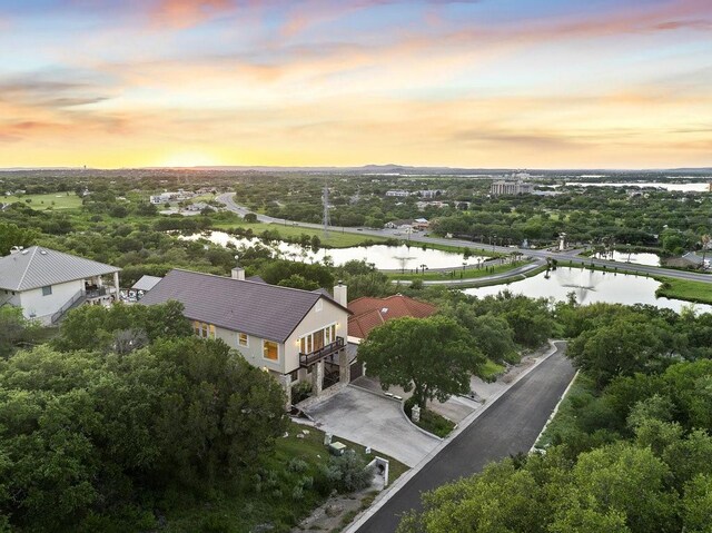 aerial view at dusk featuring a water view