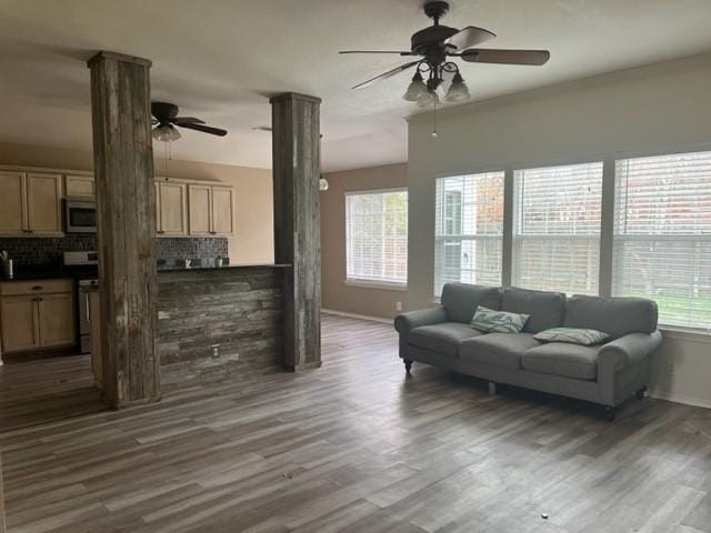 living room with ceiling fan, dark wood-type flooring, and decorative columns