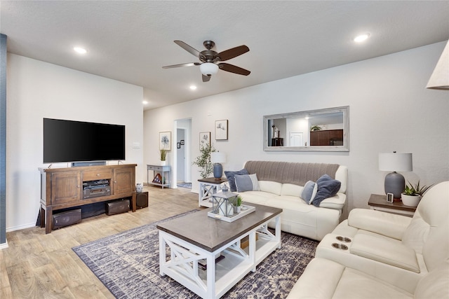 living room featuring light hardwood / wood-style floors, a textured ceiling, and ceiling fan