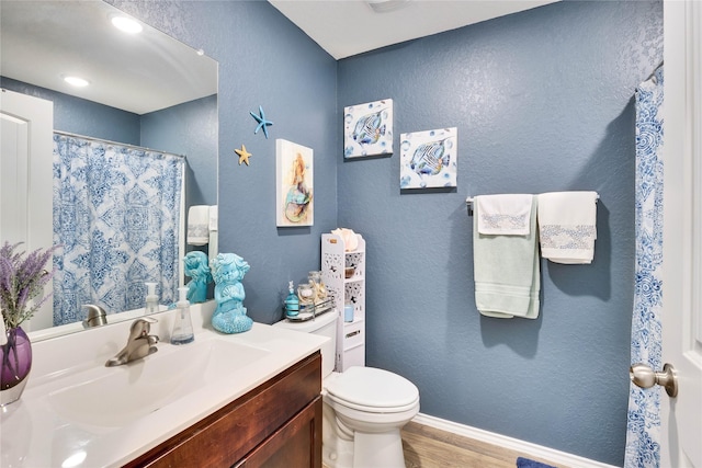 bathroom with toilet, a shower with shower curtain, hardwood / wood-style floors, and vanity