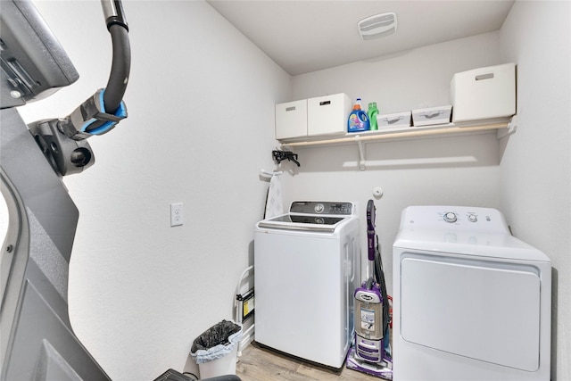 clothes washing area featuring washer and dryer and light hardwood / wood-style flooring