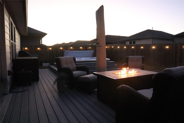 deck at dusk with an outdoor fire pit and a jacuzzi