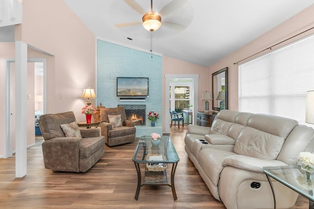 living room featuring hardwood / wood-style flooring, ceiling fan, a large fireplace, and lofted ceiling