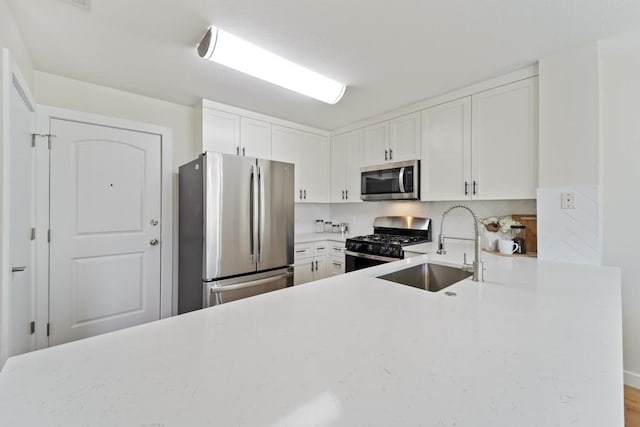 kitchen with white cabinets, stainless steel appliances, kitchen peninsula, and sink