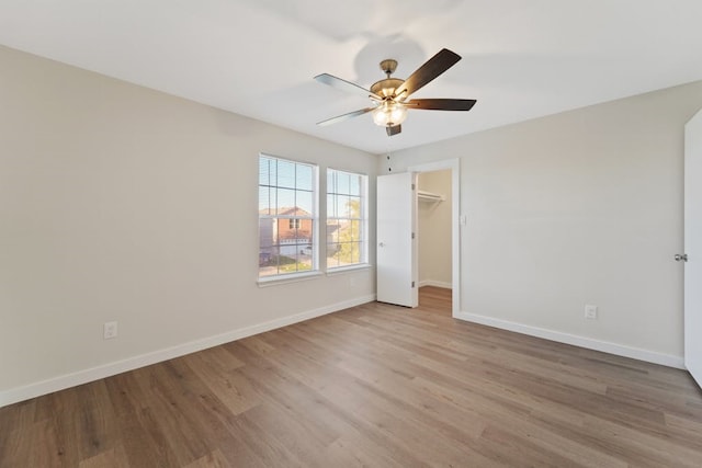 unfurnished bedroom featuring a walk in closet, ceiling fan, a closet, and light hardwood / wood-style floors