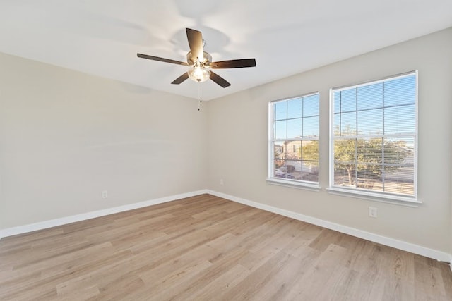 spare room with a wealth of natural light, ceiling fan, and light wood-type flooring