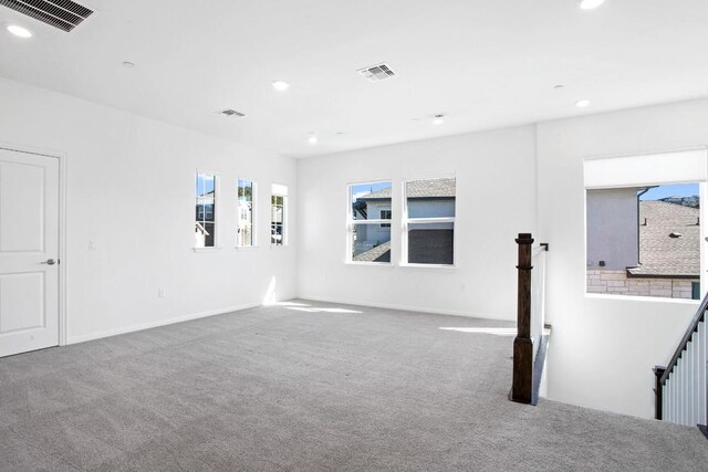 carpeted spare room featuring a wealth of natural light, visible vents, and recessed lighting