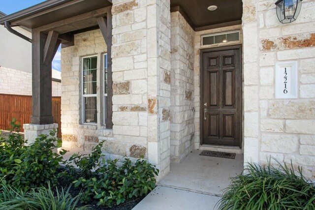 entrance to property featuring stone siding and fence