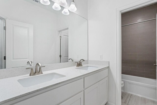 bathroom featuring double vanity, shower / bath combination, a sink, and toilet