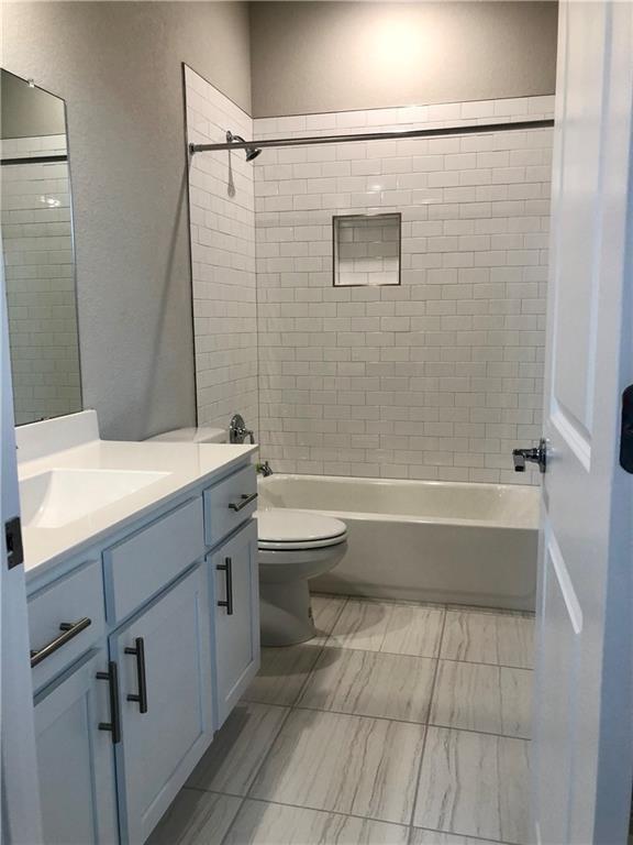 full bathroom with vanity, tiled shower / bath combo, and toilet