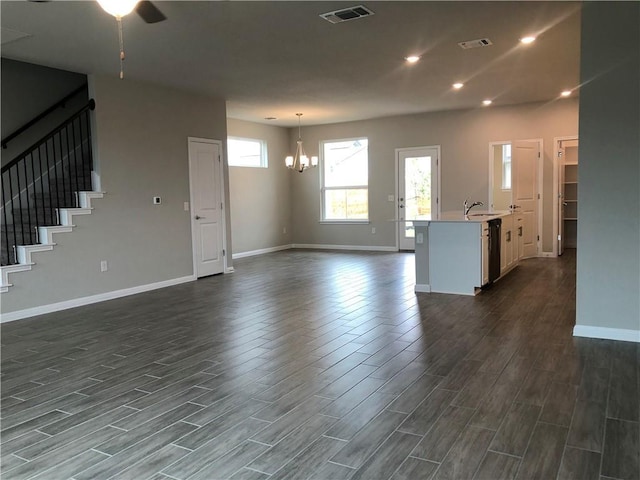 unfurnished living room featuring sink and ceiling fan with notable chandelier