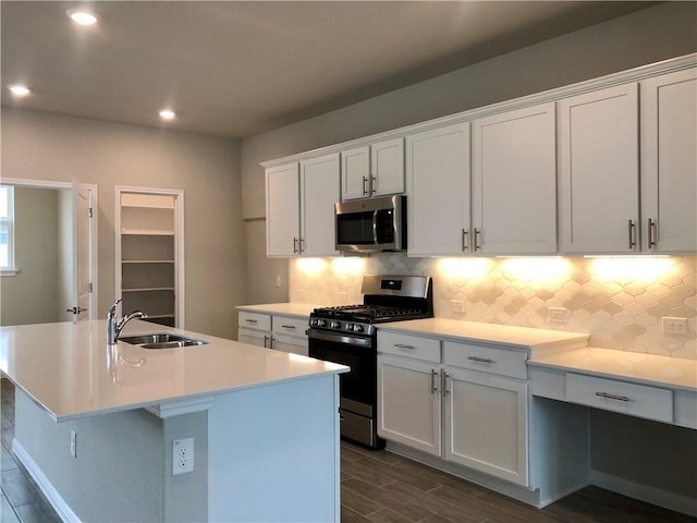 kitchen featuring white cabinets, sink, stainless steel appliances, and a kitchen island with sink