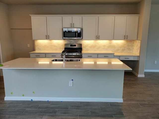 kitchen with stainless steel appliances, white cabinetry, and a kitchen island with sink