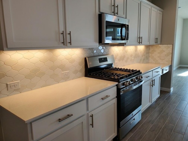 kitchen with tasteful backsplash, white cabinets, and appliances with stainless steel finishes