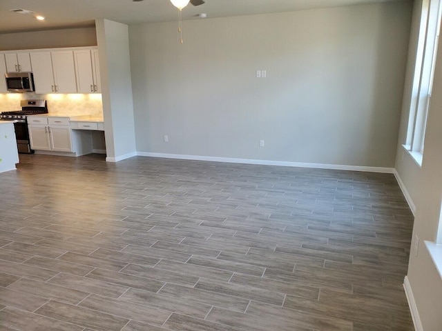 unfurnished living room with ceiling fan and built in desk