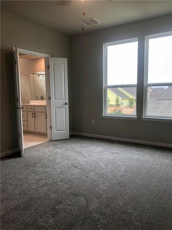 unfurnished bedroom featuring ensuite bathroom and light carpet