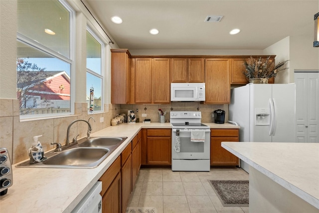 kitchen featuring decorative backsplash, light tile patterned floors, white appliances, and sink