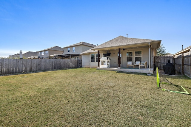 rear view of property featuring ceiling fan, a yard, and a patio