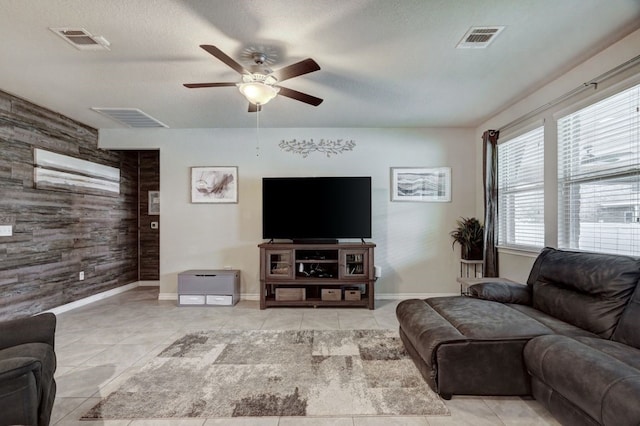 living room with an accent wall, visible vents, and tile patterned floors