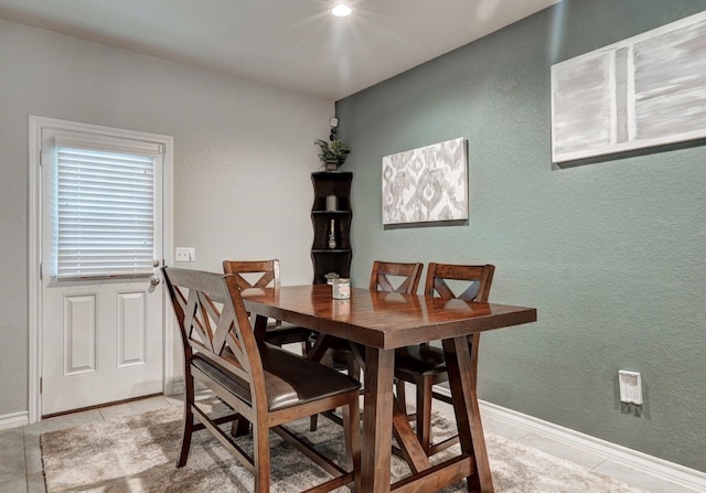 dining room with light tile patterned floors, baseboards, and a textured wall