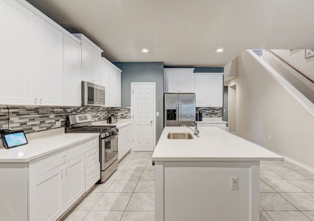 kitchen featuring stainless steel appliances, light tile patterned flooring, a sink, and a center island with sink