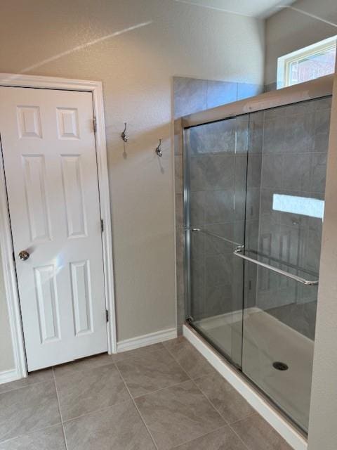 bathroom featuring a shower stall, baseboards, and tile patterned floors