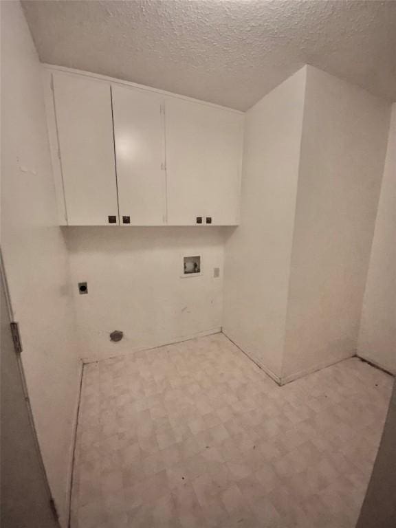 laundry room with hookup for an electric dryer, cabinets, a textured ceiling, and washer hookup