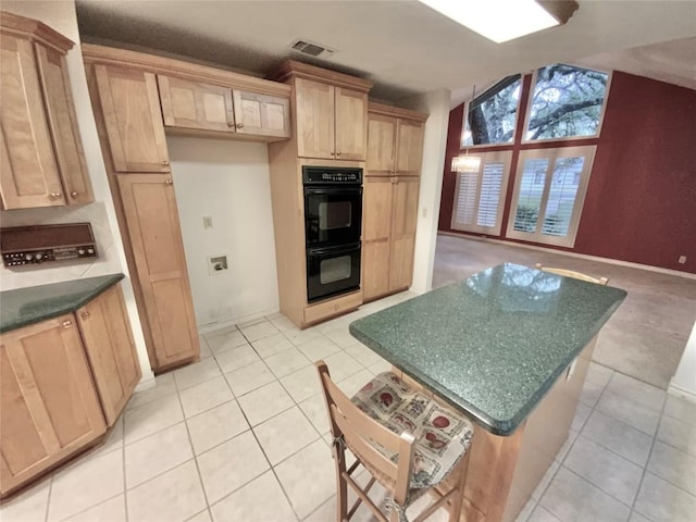 kitchen with light brown cabinets, black double oven, and light tile patterned flooring