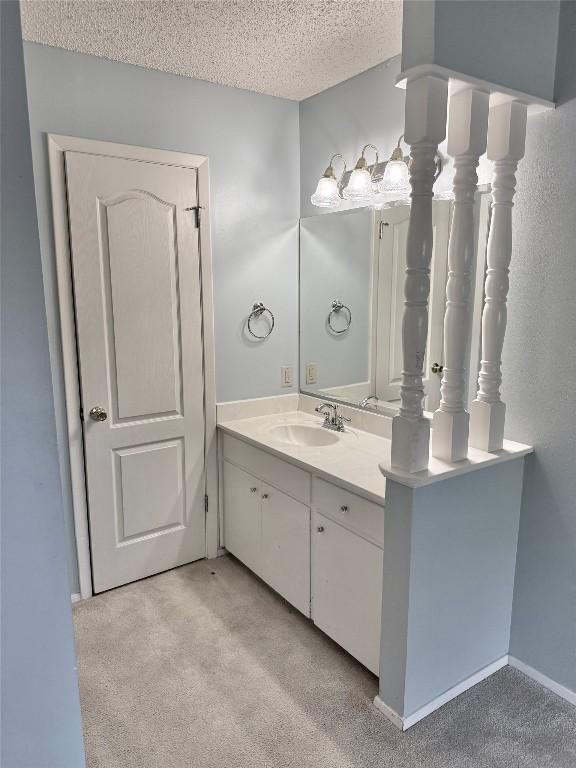 bathroom with vanity, a textured ceiling, and carpet